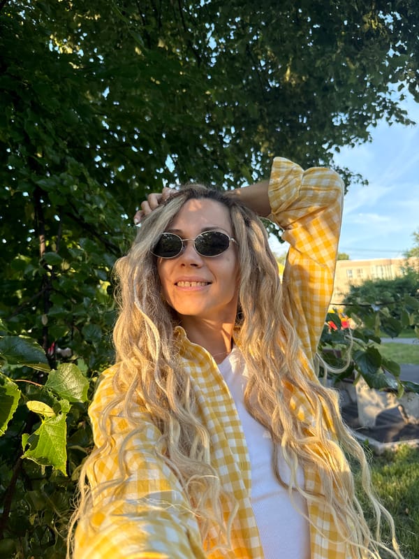 Woman takes selfie pose near green tree
