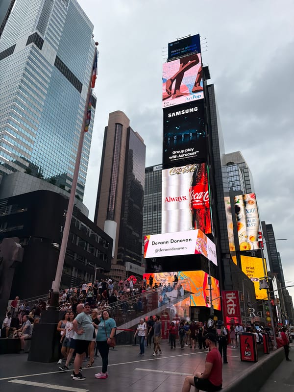 Evening traffic flows through Times Square under cloudy skies