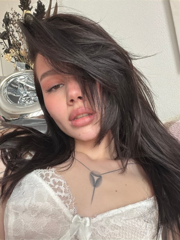 Woman in white lace photographed with tattoo, flowers visible