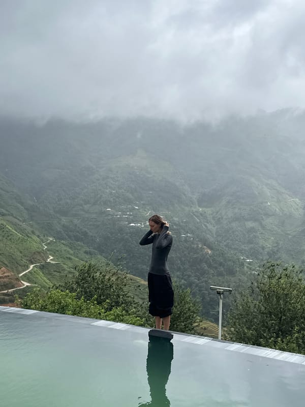 Woman at infinity pool overlooks misty Vietnam mountains