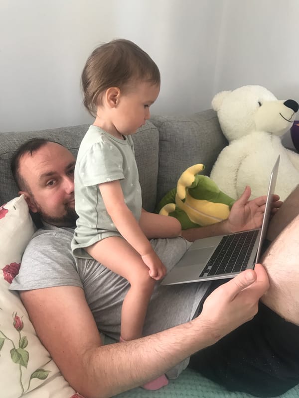 Father and baby share laptop time on sofa