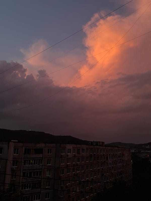 Dog watches a dramatic Vladivostok sky from the windowsill