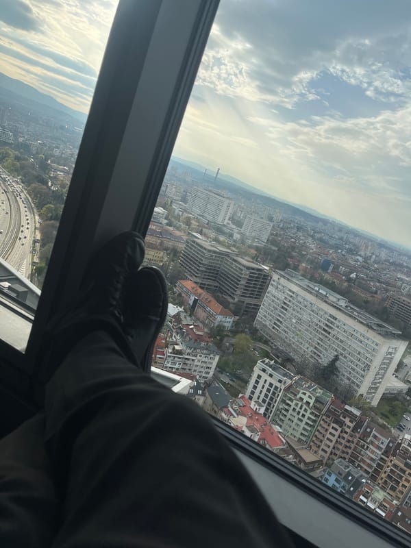 Person rests feet on window sill overlooking Sofia cityscape