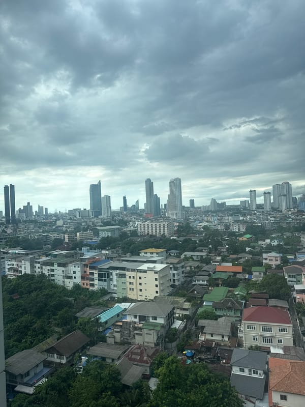 Dense Bangkok neighborhood beneath a heavy overcast sky