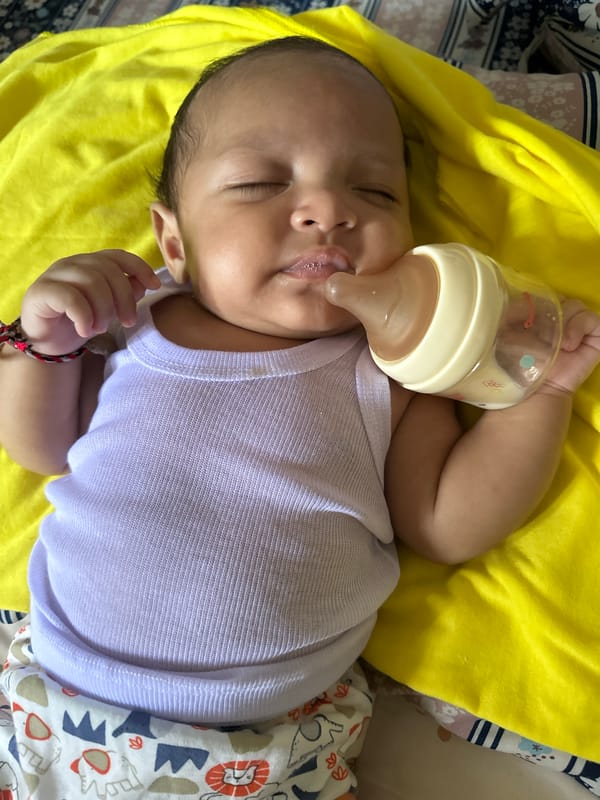 Newborn resting on a yellow blanket in cartoon elephant pants
