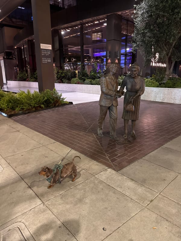 Dachshund rests near bronze statue in Beverly Hills