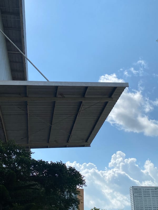 Low-angle views of a metal building and trees in Gambut Barat