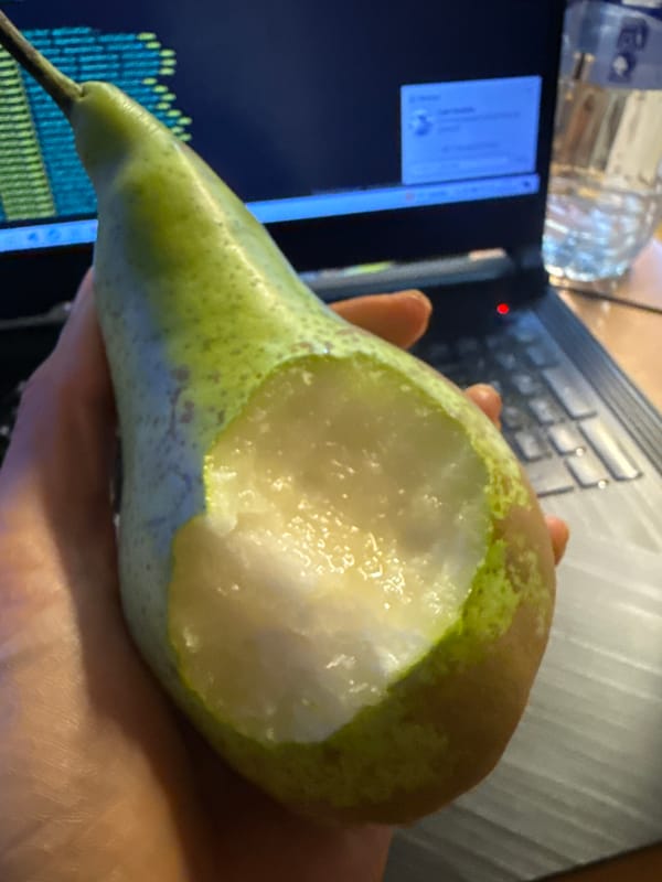 Person eats pear while coding on laptop in Barcelona