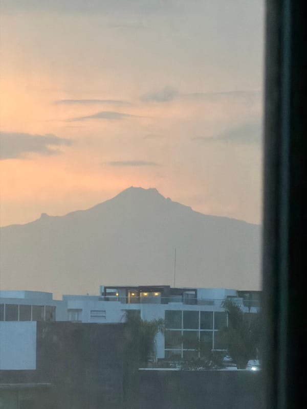 Window view captures San Andrés Cholula cityscape with mountains
