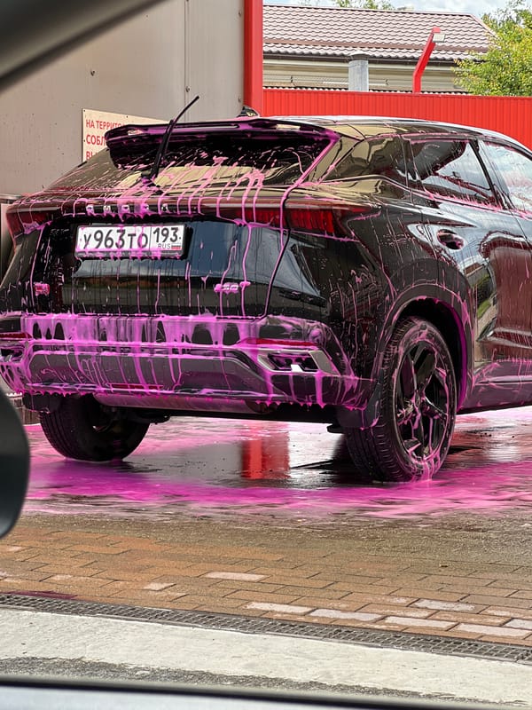Black SUV mid-wash, pink foam covering, Krasnodar car wash