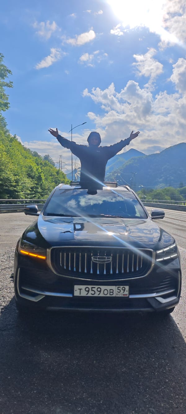 Person celebrates through sunroof on mountain road in Krasnaya Polyana