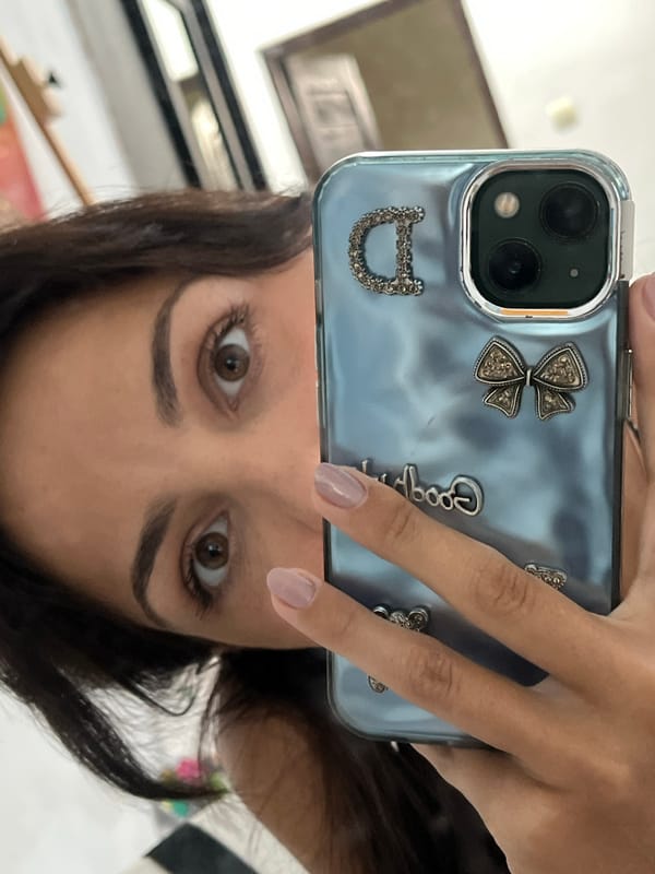 Woman takes selfies with decorated phone, cat appears in mirror
