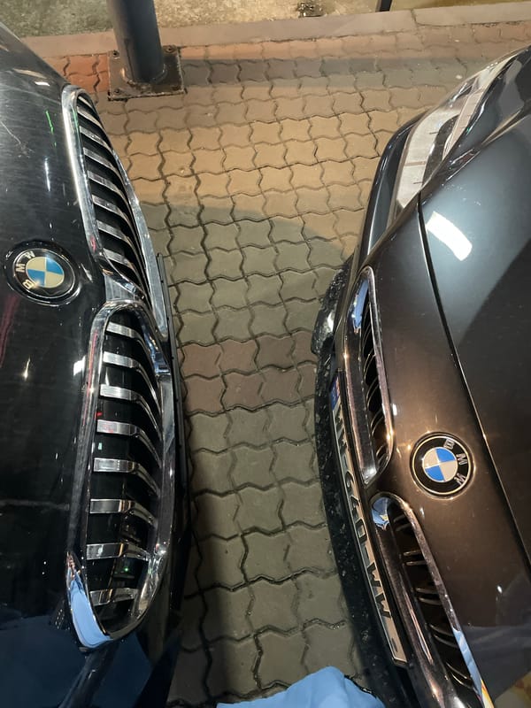 BMW cars parked near illuminated modern building in Batumi