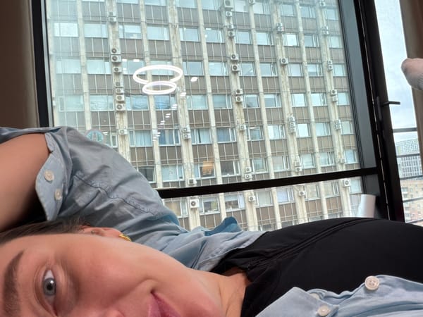 Woman rests indoors with Moscow cityscape visible through window