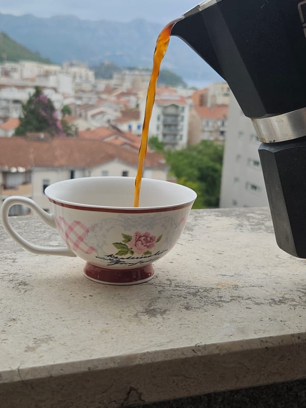Moka pot coffee poured over a misty city with red rooftops