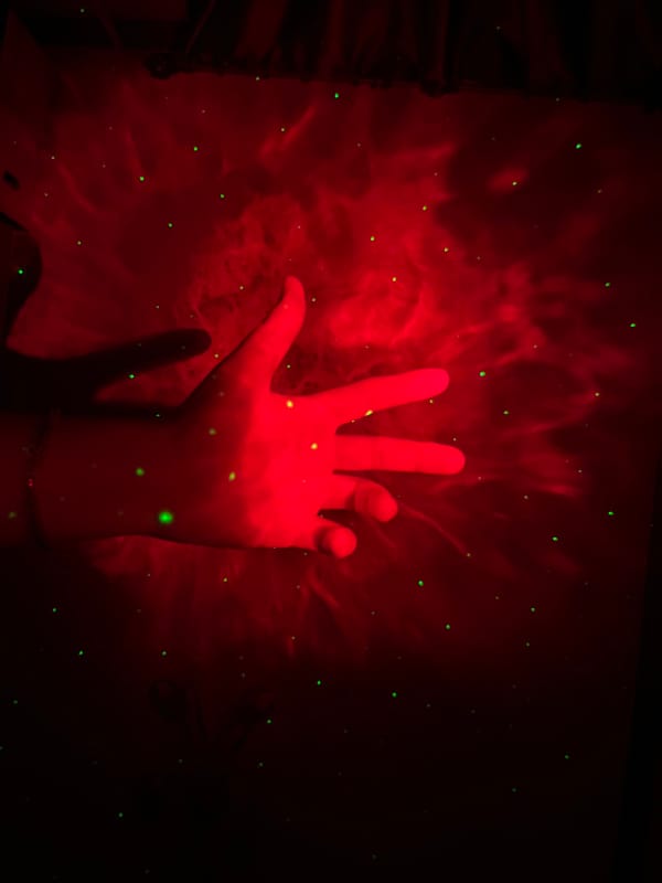 Hands play in projected nebula light at a Saint Petersburg installation