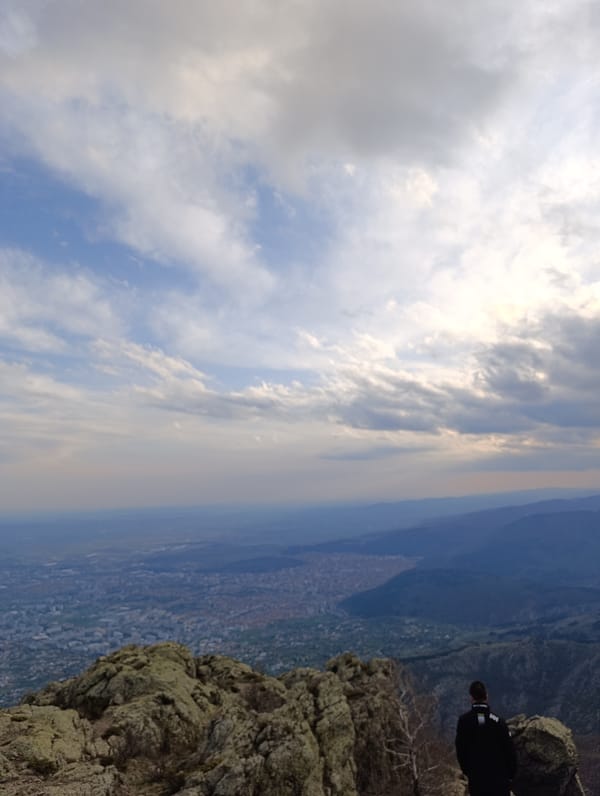 Person observes Ichera cityscape from rocky mountain terrain