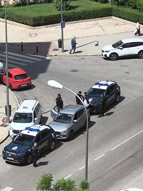 Police vehicles patrol Madrid street amid regular traffic