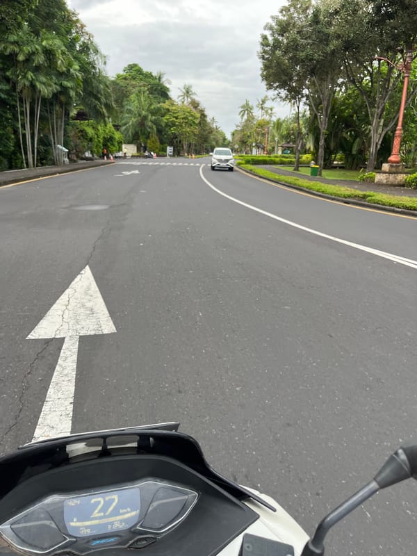 Motorcyclist rides white scooter on Kuta Selatan road