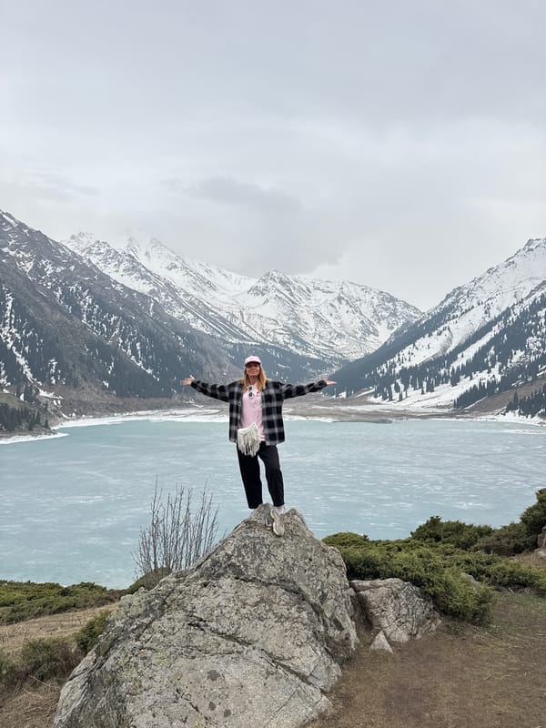 Woman poses at partially frozen Big Almaty Lake