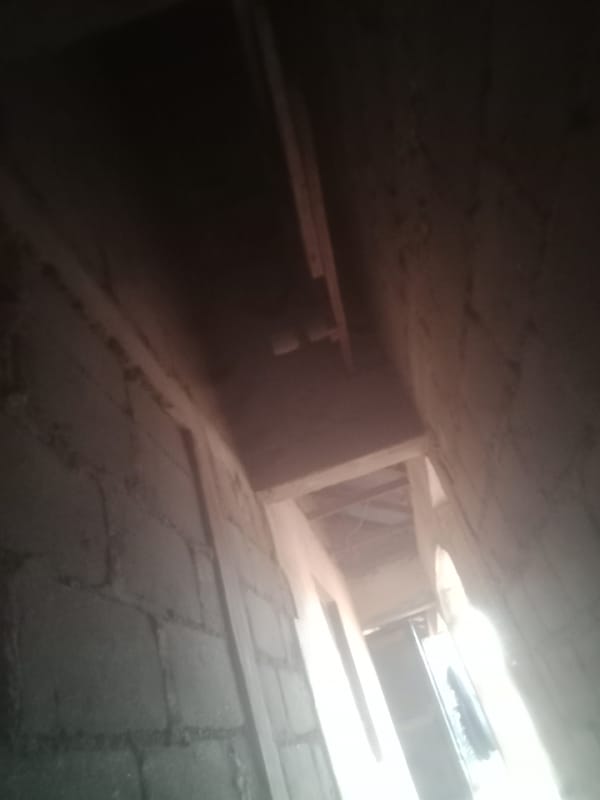 Inside an unfinished building — bare brick walls and open ceiling shaft