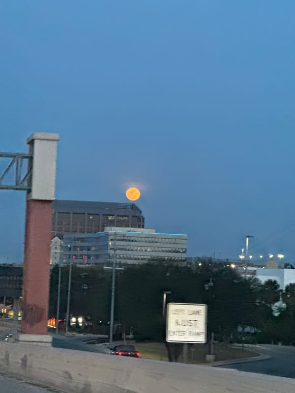 Moon visible over San Antonio skyline at dusk