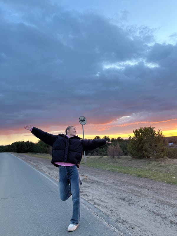 Young person stands on Russian road during dramatic sunset