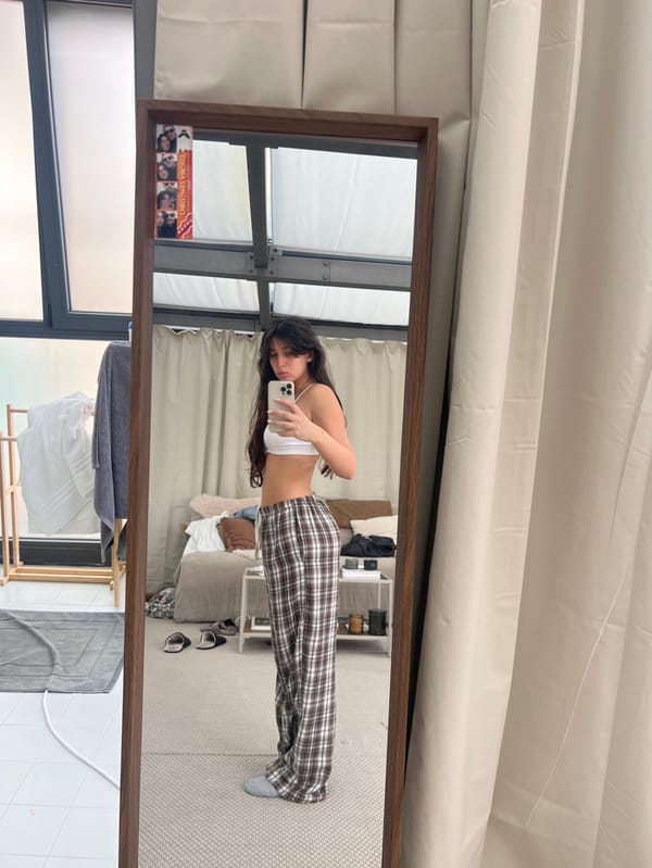 Woman photographs herself in Milan bedroom wearing white athletic wear