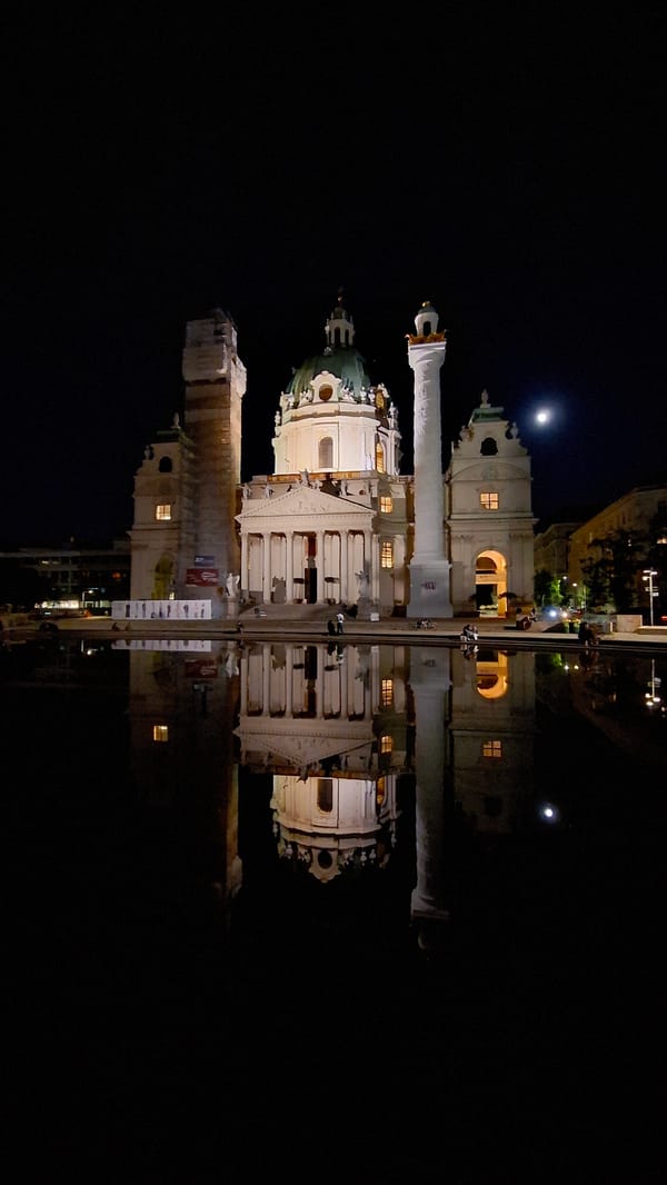 Vienna's Karlskirche reflects in water during evening illumination