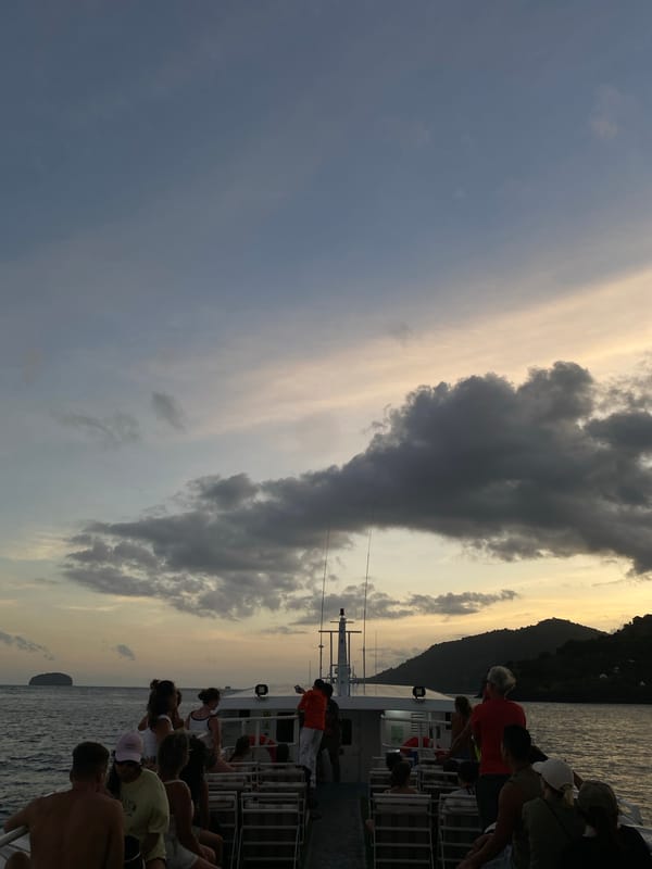 Boat passengers travel past rocky island near Karangasem Indonesia