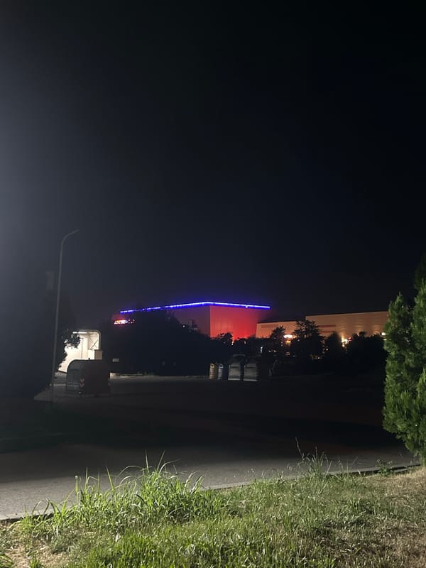 Tesla parked at night near neon-lit shops in Ruse, Bulgaria