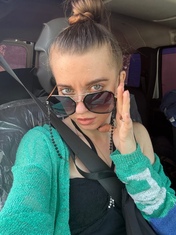 In-car moment, seatbelt on, turquoise cardigan, hand raised