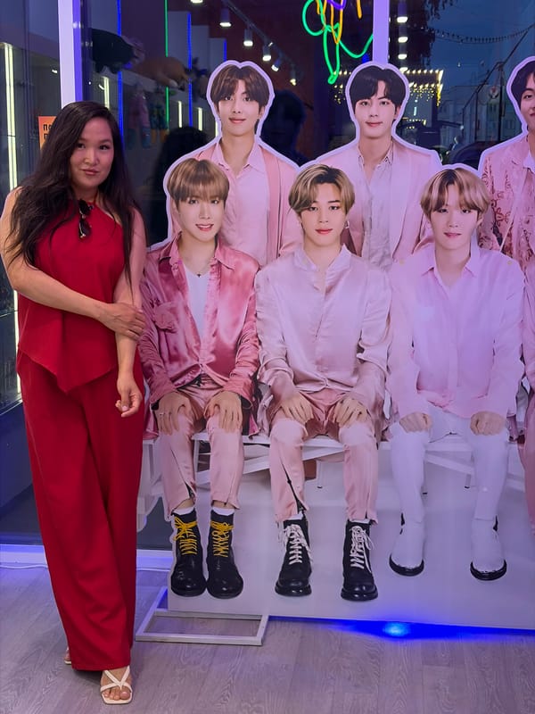 Woman in red dress lies before BTS poster