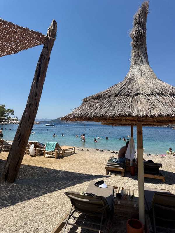 Packed pebble beach day in Fethiye under summer sun