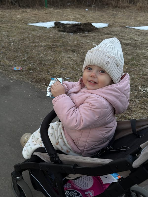 Woman films self while child plays outdoors in Reshetnikovo