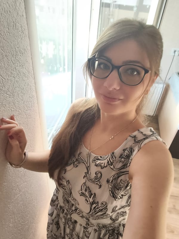 Posed against a textured wall in a floral dress