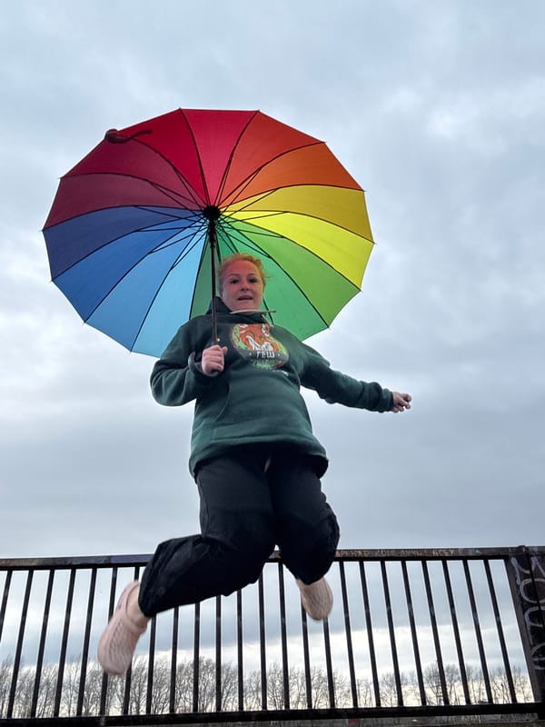 Woman with rainbow umbrella photographed by water in Chaikovsky