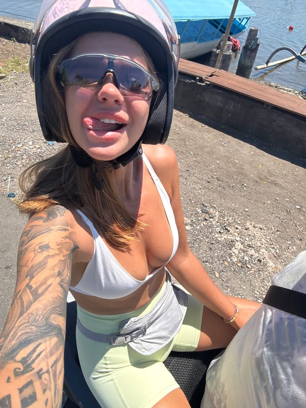 Woman photographs herself on motorcycle near Denpasar harbor