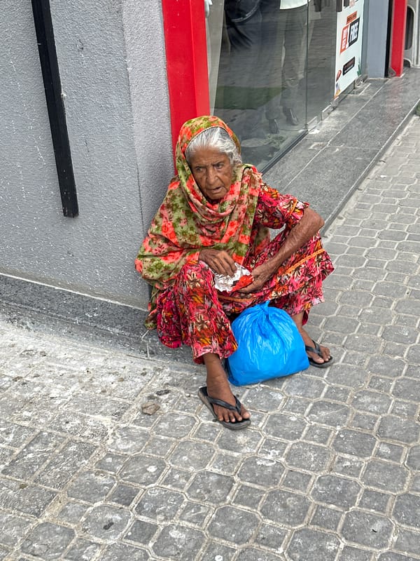 Resting against a wall in Karachi, dressed in floral shalwar kameez