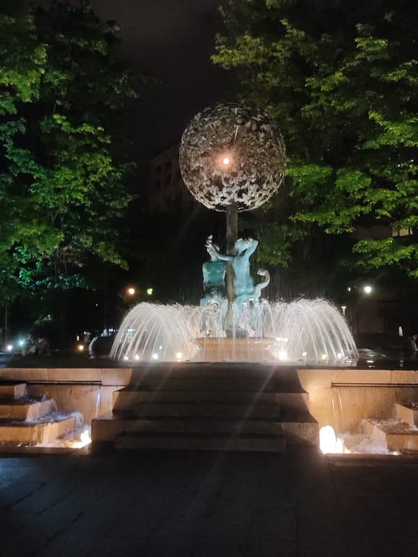 Illuminated Moscow fountain with sculptural figures observed at night