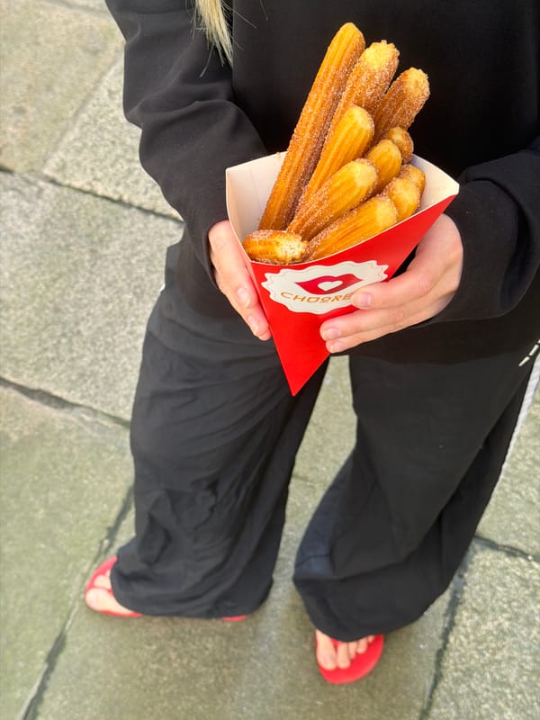 Person enjoys churros on Santiago De Compostela sidewalk