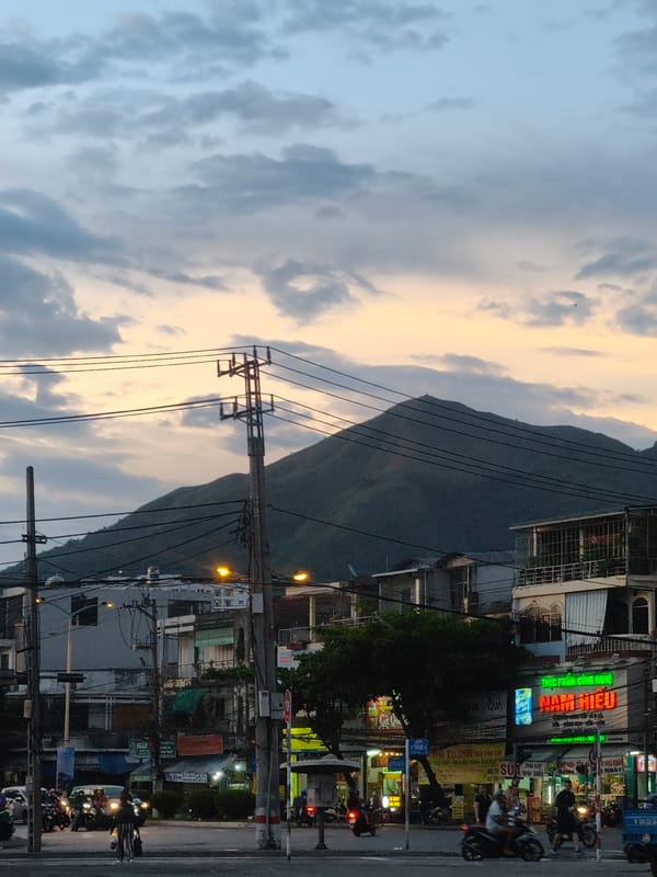 City streets at dusk with mountain silhouettes and sunset sky