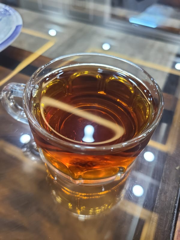 Three suited men gather on sofa in Quetta indoor setting