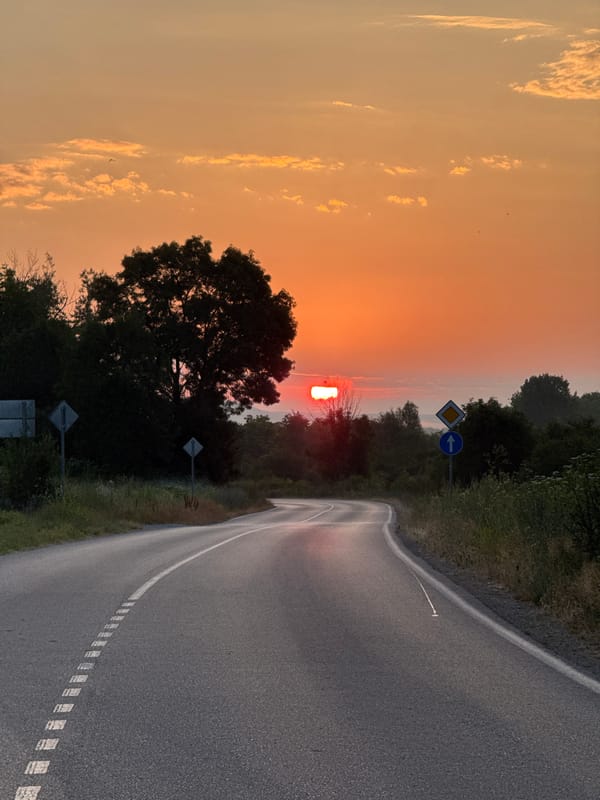 Winding rural road under a warm sunset sky