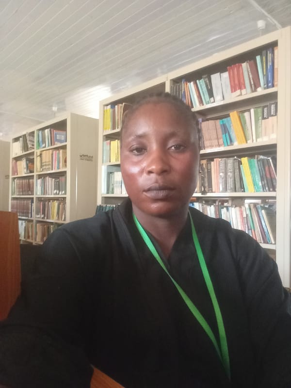 Person photographed with green lanyard near books in Akwanga