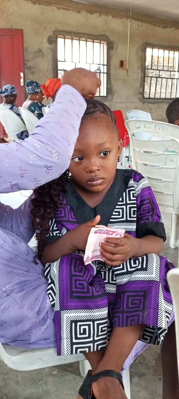 Child holds banknote indoors in Lokoja, Nigeria