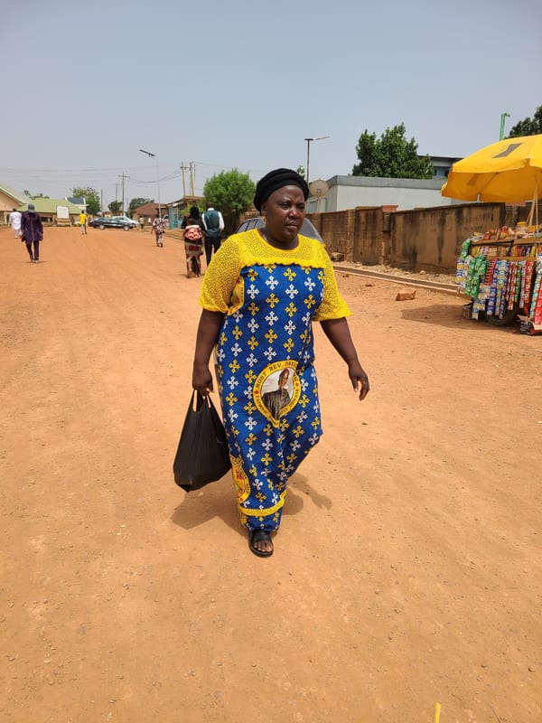 Two pedestrians spotted on dirt street in Jos, Nigeria