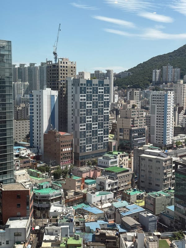 Aerial views over Busan's dense urban skyline and mountain backdrop