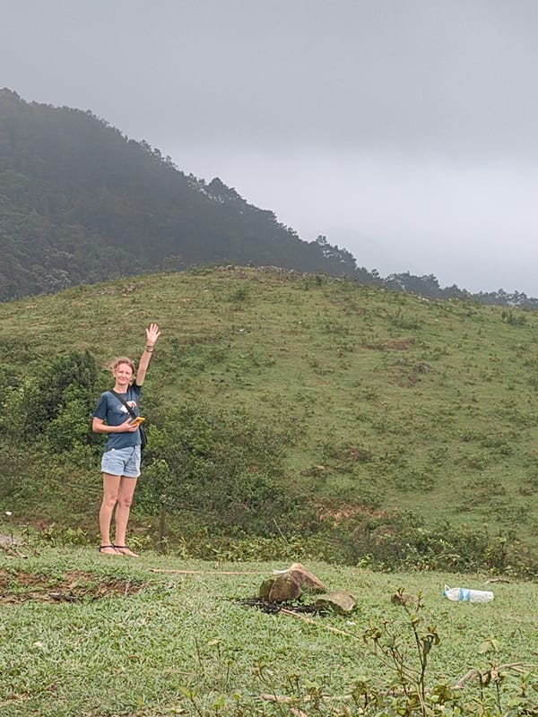 Woman waves near resting water buffalo in Vietnamese commune