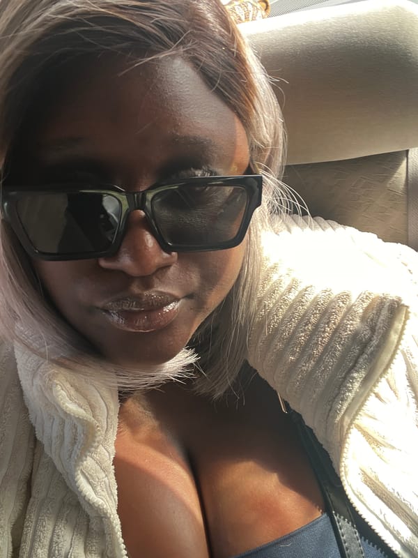 Woman rests in vehicle wearing sunglasses in Nabatum, Nigeria